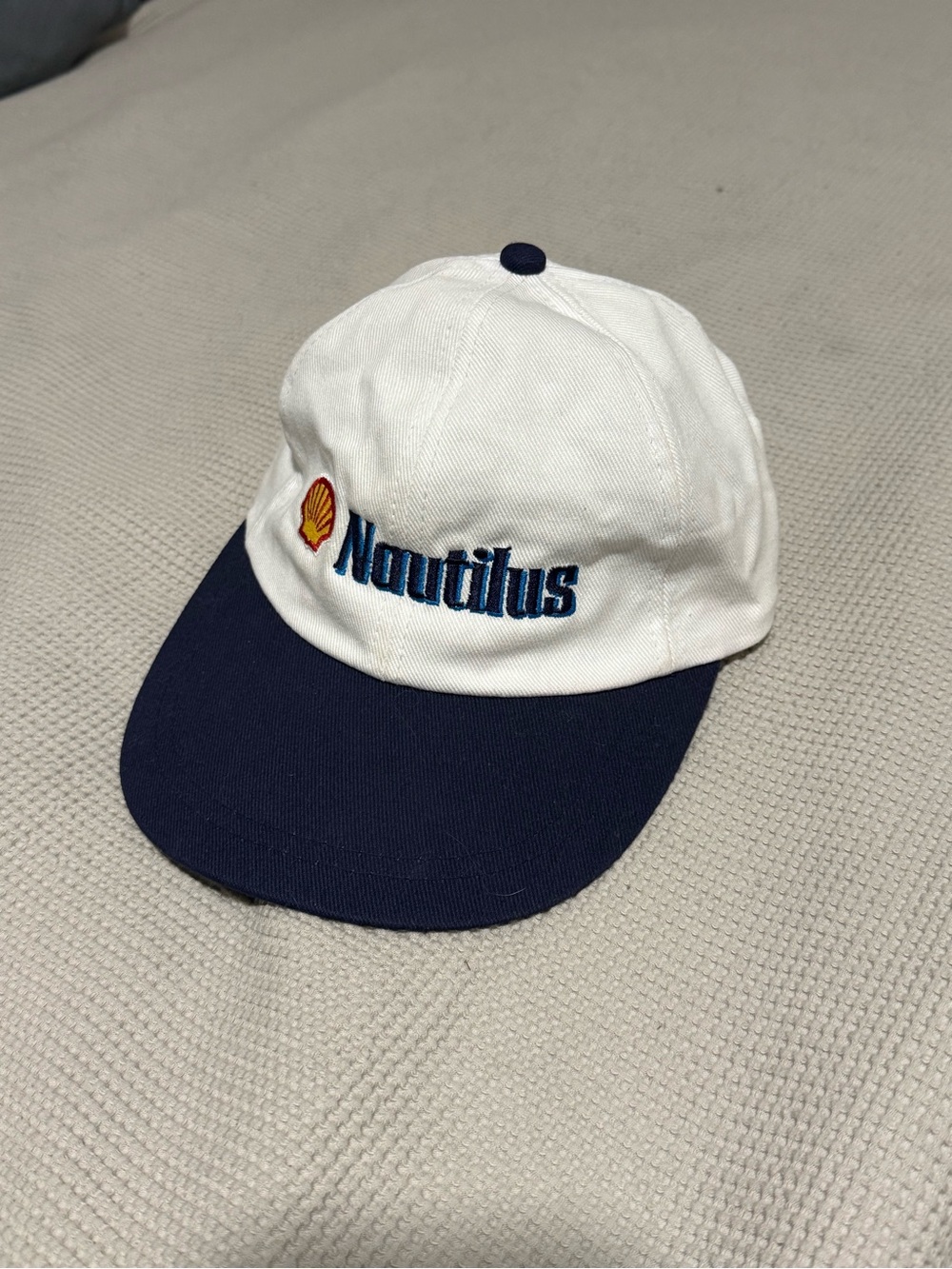 She’ll Nautilus White and Navy Logo Baseball Cap